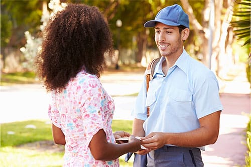 Woman exchanging envelope with mailman.