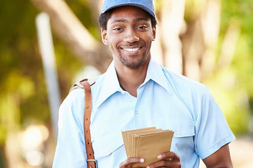 Happy mailman with satchel on shoulder and envelopes in hand.
