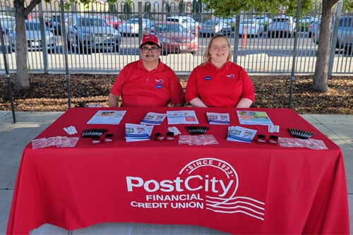 Post City Financial CU employees sitting at table with marketing materials.