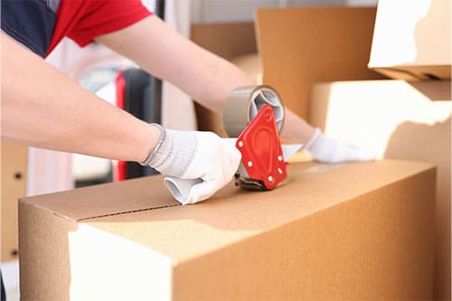 Person sealing box with packing tape.