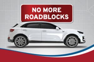 "No More Roadblocks" sign next to white Sport Utility Vehicle