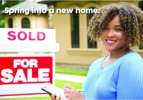 Woman standing in front of For Sale signage