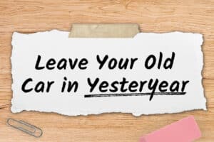 A wooden desk features a torn paper with "Leave Your Old Car in Yesteryear."